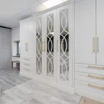 White fitted wardrobes with mirrored fretwork doors and brass handles