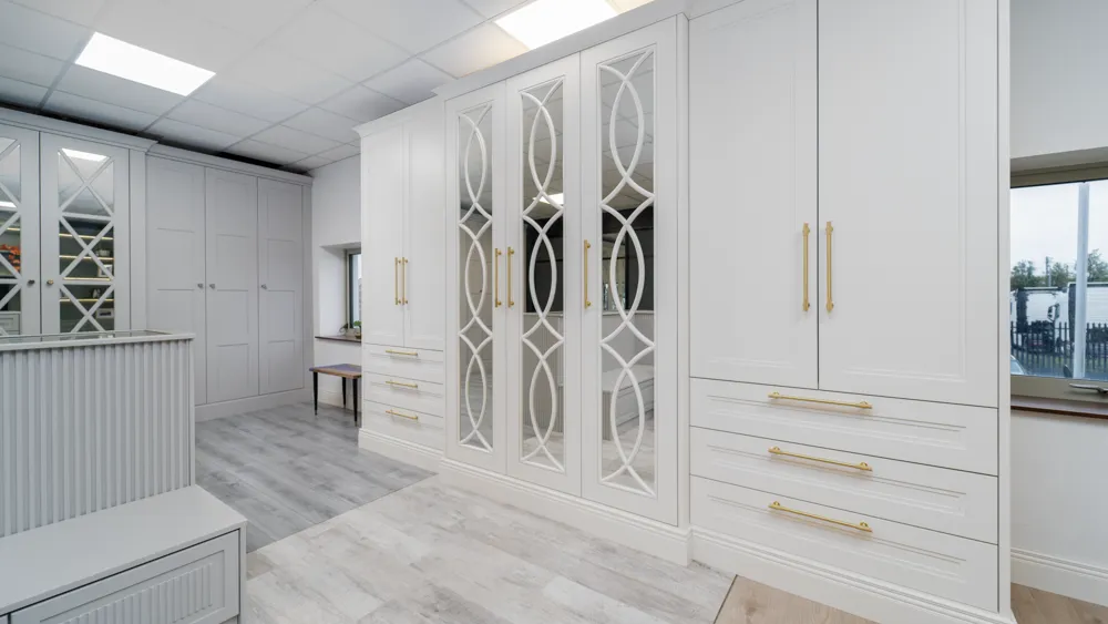 White fitted wardrobes with mirrored fretwork doors and brass handles